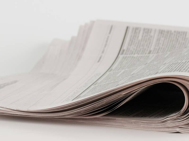 Eine gefaltete Zeitung liegt leicht geöffnet auf einem weißen Hintergrund.