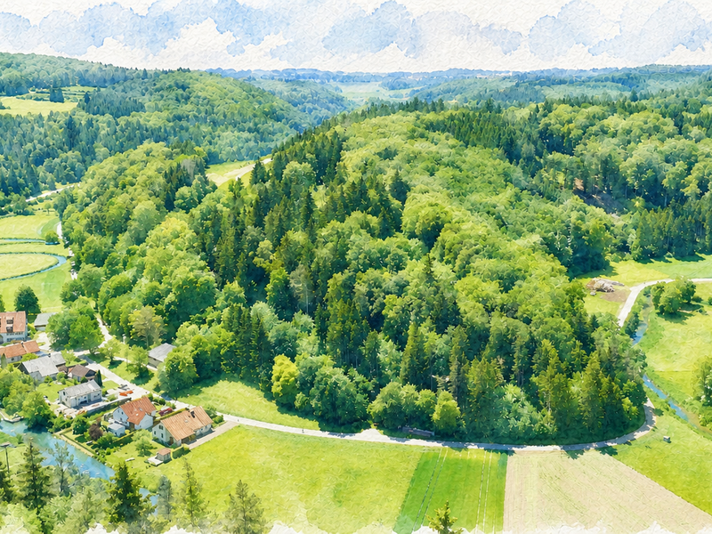 Eine von Wäldern und Hügeln umgebene kleine ländliche Siedlung liegt in einer weitläufigen, grünen Landschaft.